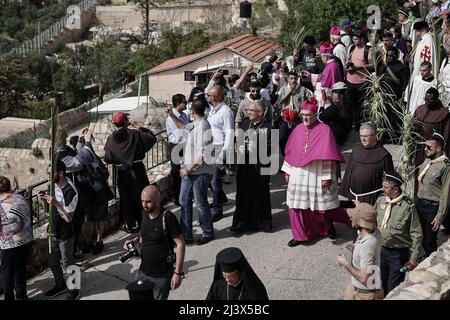 Jerusalem, Israel. 10th April, 2022. Latin Patriarch of Jerusalem, PIERBATTISTA PIZZABALLA (center - purple clergy robe) joins thousands of Christian pilgrims celebrating Palm Sunday descending from the Mount of Olives towards biblical Jerusalem, as they retrace the steps of Jesus. The procession began at the 4th century Bethphage Church, on the eastern slopes of the Mount of Olives, traditionally the place where Jesus began his triumphant entry into Jerusalem, ascended to the summit and then descended westward to Gethsemane, the Lions' Gate and to the Church of St. Anne. Credit: Nir Alon/Ala Stock Photo