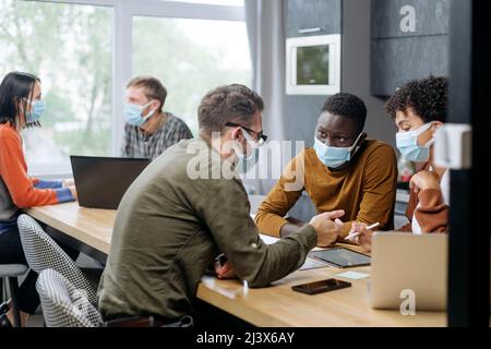 employees in protective masks work in the hall of the coworking center. Stock Photo