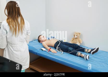 Child undergoing electrocardiogram test in pediatric clinic Stock Photo