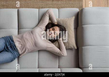 Happy relaxed pretty young woman lying on sofa at home Stock Photo