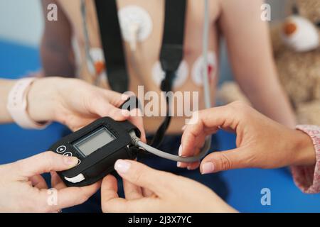 Doctor showing ECG holter monitor to patient in pediatric clinic Stock Photo
