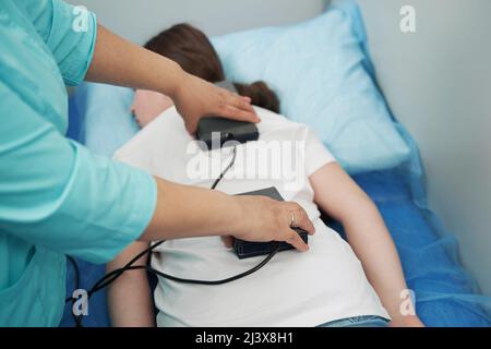 Doctor performing magnetic therapy procedure in clinic Stock Photo