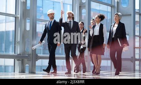 Team of construction industry workers engineer architect business people professionals walking together in modern lobby Stock Photo