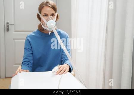 Woman using breathing therapy medical device in clinic Stock Photo