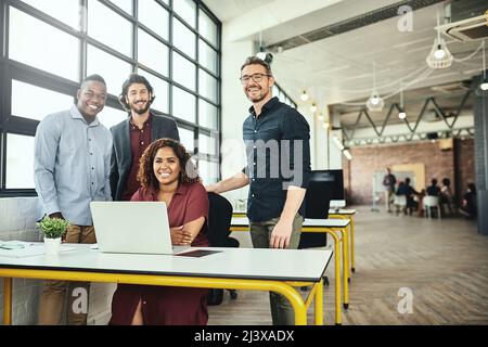 Were the only team you need. Cropped portrait of a group of businesspeople standing around a desk in their office. Stock Photo