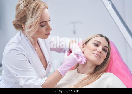 Dermatologist in nitrile gloves conducting mesotherapy procedure Stock Photo