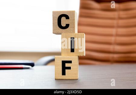 CIF Cost, Insurance and Freight acronym on wooden cubes on columns of numbers background. CIF Cost, Insurance and Freight acronym on wooden cubes. bac Stock Photo