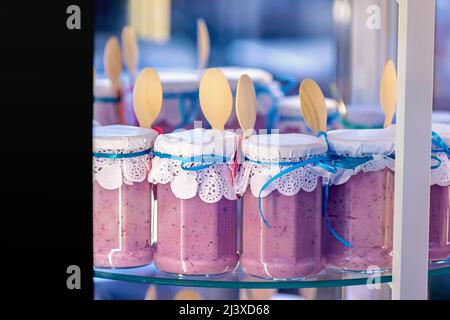 Pink dessert in jars with wooden spoons.Shallow depth of field Stock Photo