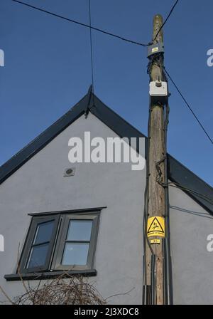 warning sign on pole with electrical cables, england Stock Photo