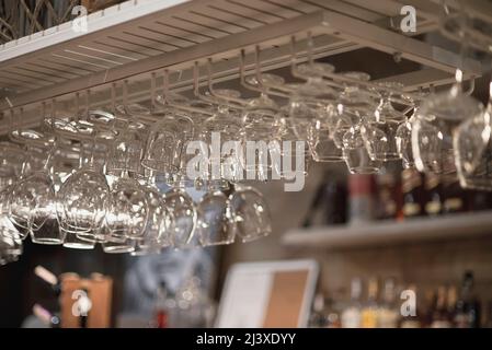 A row of empty glasses hang over the bar counter Stock Photo