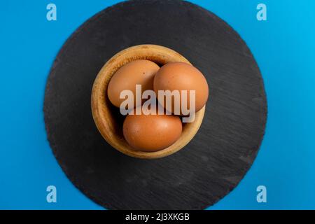 Hard boiled eggs in a wooden bowl on a round slate plate. There were perfectly fine eggs, just cracks and crevices until the white of the egg was Stock Photo