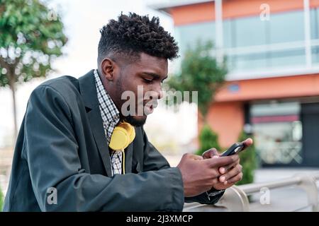 Outdoor portrait of a young black African-American man talking on his mobile phone, writing on his smartphone in the city. social network concept Stock Photo
