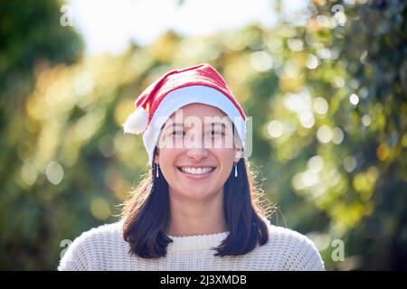 Not every Christmas is covered in snow. Portrait of a young woman celebrating Christmas in a garden. Stock Photo