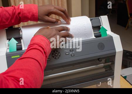 Close-up of a blind person reading Braille script Poster Print straight out of a braille embosser Stock Photo