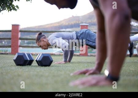 Having a workout partner pushes me to do better. Shot of two men working out and doing pushups together. Stock Photo