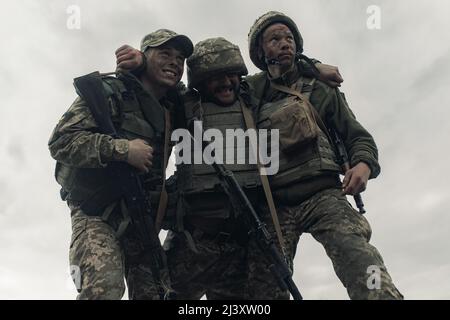 Two Ukrainian soldiers drag wounded warrior after battle against russian enemy. Concept of russian military invasion in Ukraine. War in Ukraine and Eu Stock Photo