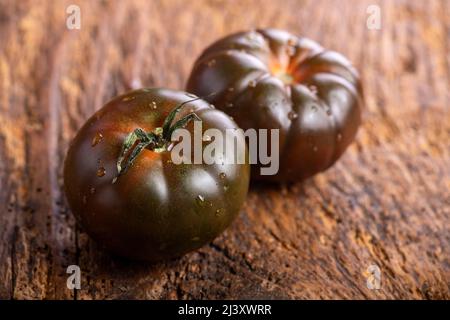 black tomatoes on dark wood Stock Photo