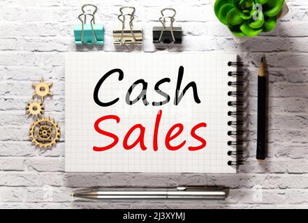 On the table there is a red marker and a white paper tablet on which the text is written - CASH sales, red and black letters. Business concept. Stock Photo