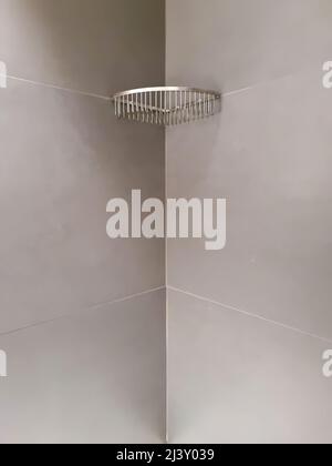 Chrome wire basket for soap and toiletries hanging in a corner of a modern designed bathroom Stock Photo