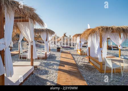 Canopy beach bed with white curtains on an empty beach in summer Stock Photo
