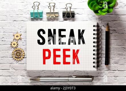 The phrase Sneak Peek appearing behind torn paper Stock Photo