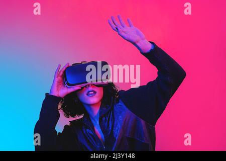The young woman is using virtual reality viewer. Modern woman portrait with trendy look and bright colors. Stock Photo