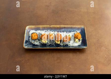 Delicious prawn croquettes served marine style on mussel shells, coarse salt and a blue plate Stock Photo