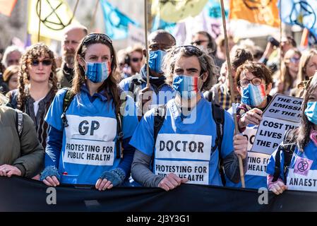 Extinction Rebellion protesters launching period of civil disruption in London from 9 April 2022. Doctors at front of march with public health signs Stock Photo