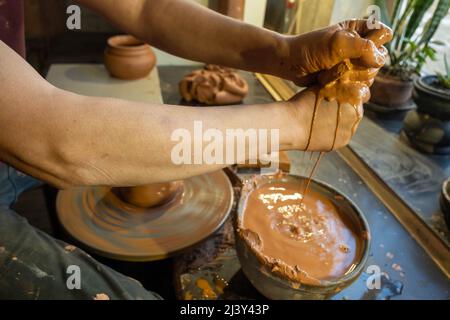 Closeup of potter makes pottery dishes on potter's wheel. Master and apprentice learning clay crafting. Stock Photo