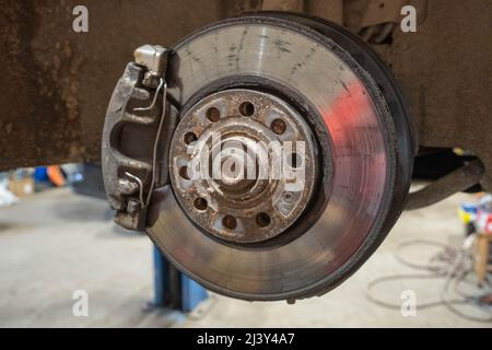 Disc brake of the vehicle for repair, in process of new tire replacement. Car brake repairing in garage.Close up Stock Photo