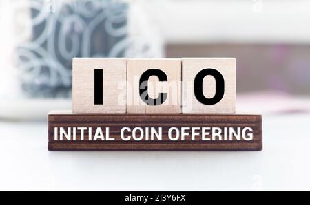 ICO abbreviation stands for Initial Coin Offering on wooden blocks, yellow background. Cryptocurrencies concept. Stock Photo