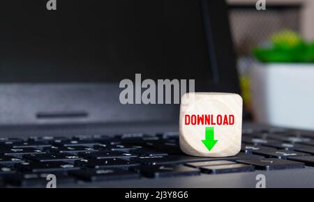 Conceptual Download Text with Arrow Down on Small Wooden Cube Above Computer Keyboard. Isolated on White. Stock Photo