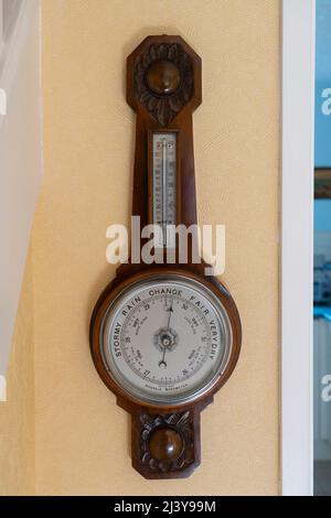 British made antique aneroid barometer with a face showing stormy, rain, change, fair and very dry, currently forecasting a change in the weather. UK Stock Photo