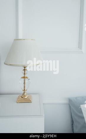 bedside table in the bedroom with a lamp.  Minimalist style. classic light interior Stock Photo