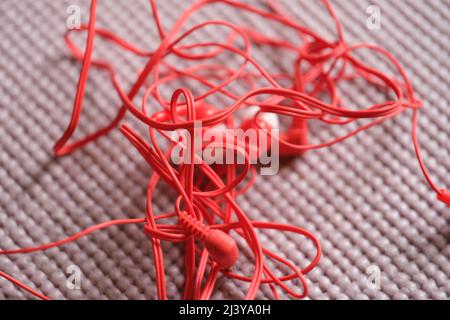 Tangled red wired headphones on gray background Stock Photo