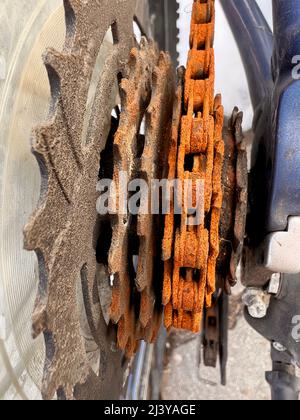 Blue bike has been outside all winter and got broken. Rusty bicycle chain hangs on sprocket and gear. Stock Photo