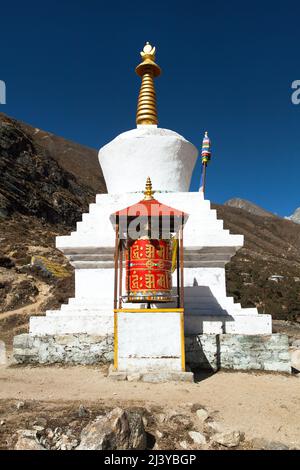 Buddhist stupa and prayer wheel in Thame village, Khumbu valley on three passes trek, Mount Everest area, Sagarmatha national park, Nepal Stock Photo