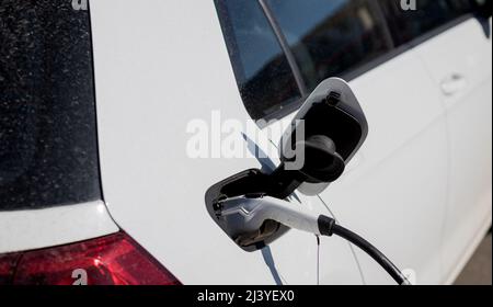 Power cable pump plug in charging power to electric vehicle. Electric car charging on parking lot Stock Photo