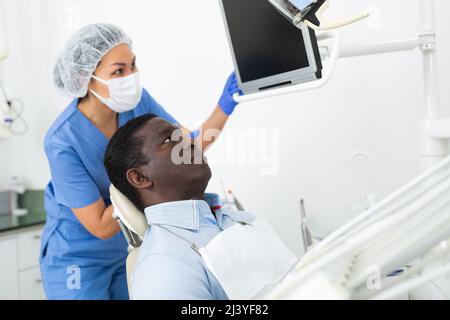 Female stomatologist showing teeth radiography result on computer to patient Stock Photo
