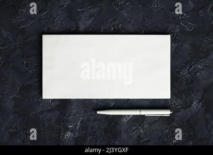 Photo of blank paper envelope and pen on black plaster background. Blank stationery template. Top view. Stock Photo