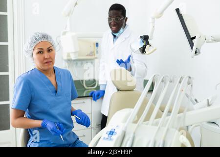 Upset woman in blue uniform standing in dental office with dissatisfied dentist Stock Photo