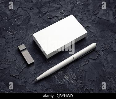 Blank business card, usb flash drive and pen on black plaster background. Mockup for branding identity. Template for graphic designers portfolios. Stock Photo