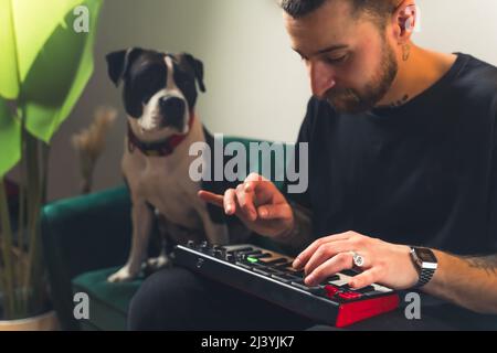 European male musician dj creating music on his sofa with his dog on the side. Creativity concept. High quality photo Stock Photo