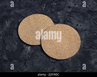 Photo of blank cork beer coasters on black plaster background. Stock Photo