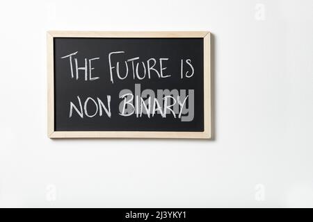 Blackboard hanging on a white wall with the text The future is non binary written on it in chalk. Concept of respect for gender diversity. Stock Photo