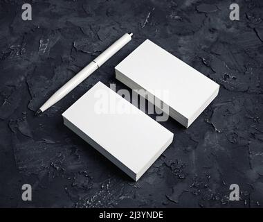 Blank stationery set. Photo of blank business cards and pen on black plaster background. Stock Photo