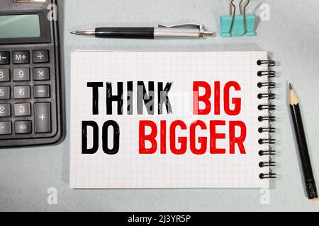 Think Big, Do Bigger Motivation quote written on a note paper. Stock Photo