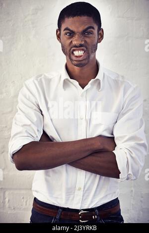 Ive had just about enough. Shot of a serious young man standing with his arms crossed. Stock Photo