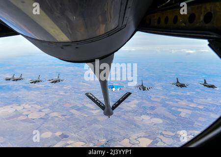 Eight F-16 Fighting Falcons assigned to the 114th Fighter Wing, fly behind a KC-135 Stratotanker from the 185th Air Refueling Wing while traveling to Weapons and Tactics Instructor (WTI) course 2-22 at Marine Corps Air Station Yuma, Ariz., April 1, 2022. WTI is a seven-week training event hosted by Marine Aviation Weapons and Tactics Squadron One (MAWTS-1), providing standardized advanced tactical training and certification of unit instructor qualifications to support Marine aviation training and readiness, and assists in developing and employing aviation weapons and tactics.  (U.S. Air Nation Stock Photo