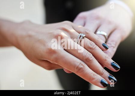 Showing off the symbol of their union. Cropped shot of a newlywed couple wearing their wedding rings. Stock Photo
